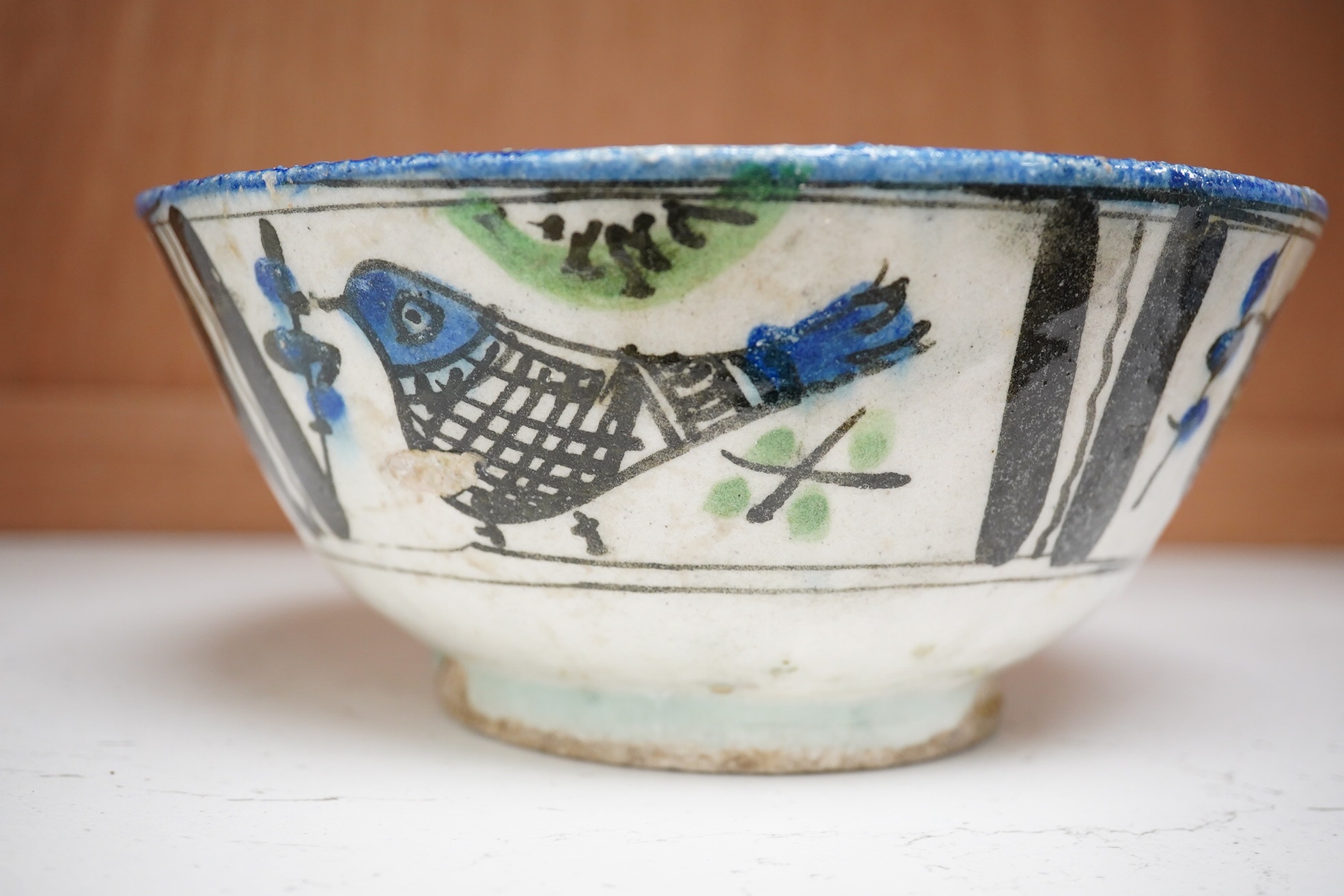 An 18th century Persian pottery bowl with bird decoration, 19cm diameter. Condition - poor